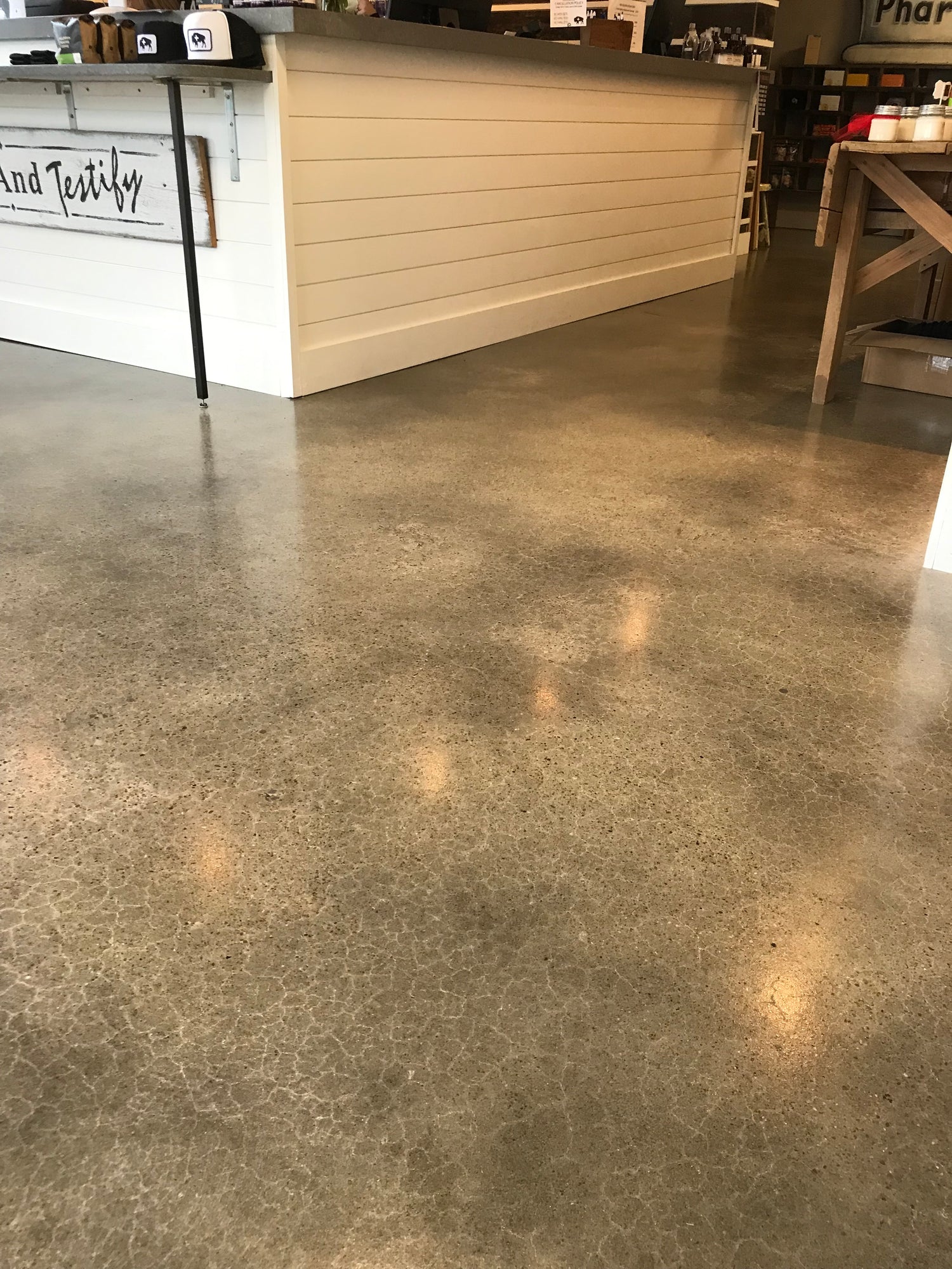 Commercial interior space with HydroSeal epoxy interior concrete coating from U.S. Surface Technologies, showing polished and sealed concrete floor near counter and table.