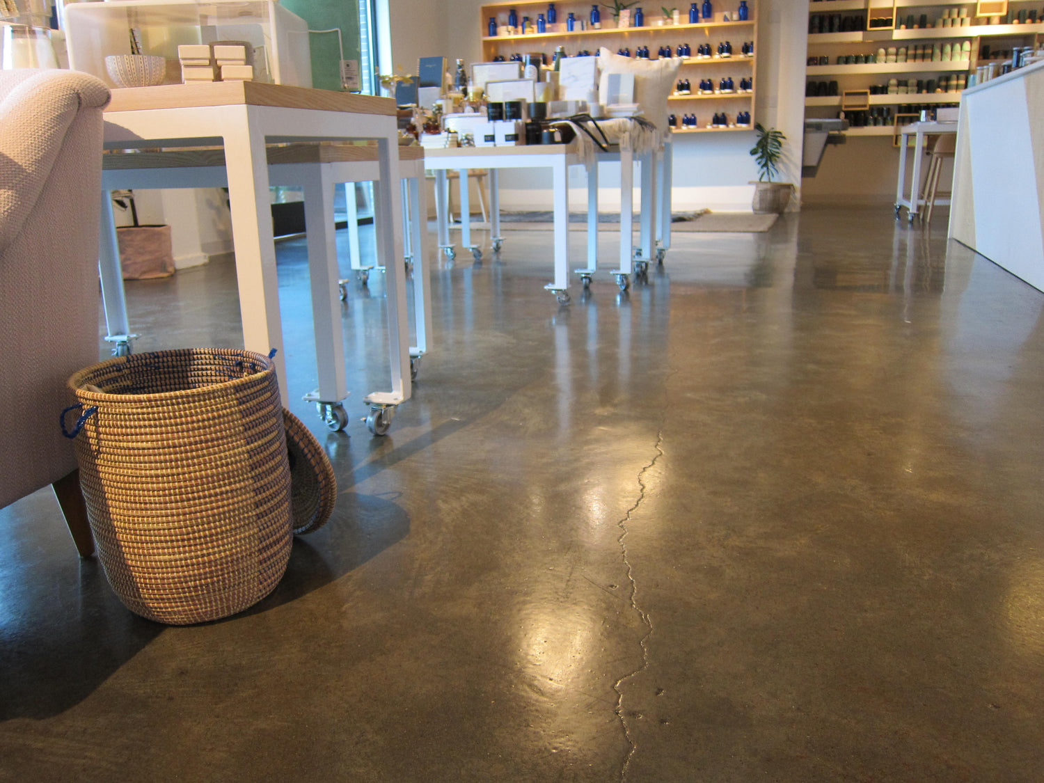 Modern commercial interior with polished and epoxy-sealed concrete floor finished with interior concrete coatings from U.S. Surface Technologies, featuring tables, chairs, and wicker basket.